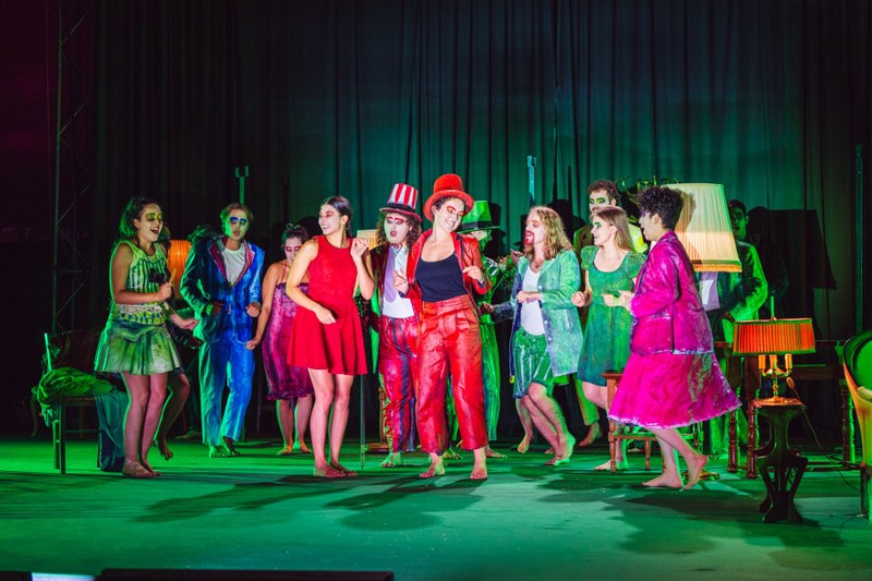 Eine Gruppe Leute mit bunten Kostümen posiert auf einer Bühne