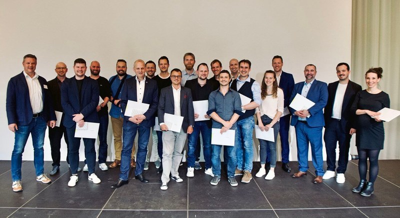 Diplomierte stehen mit Zeugnissen herum