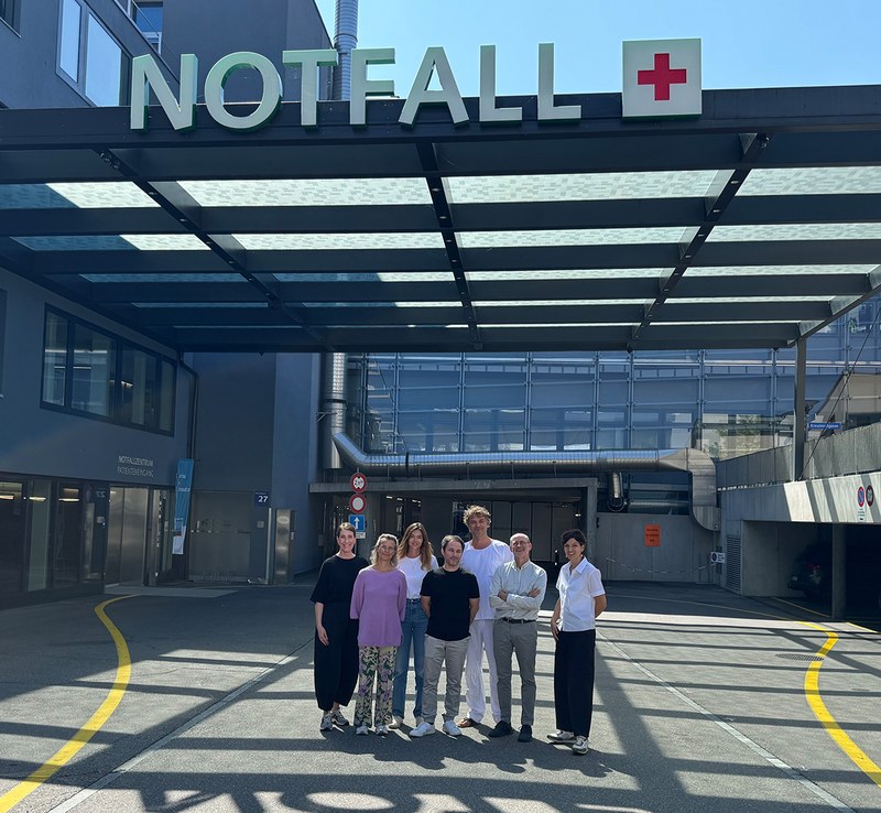 Das Projektteam bestehend aus sieben Personen stehen vor dem Notfall-Eingang eines Krankenhauses.