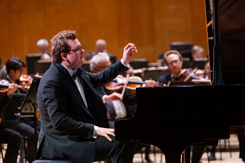 Edward Toth beim Auftritt am Flügel mit einem Orchester im Hintergrund