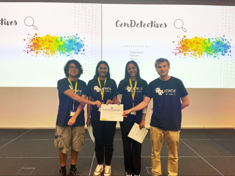 Das Gewinnerteam steht zu viert nebeneinander auf der Bühne und hält gemeinsam die Siegerurkunde in den Händen.