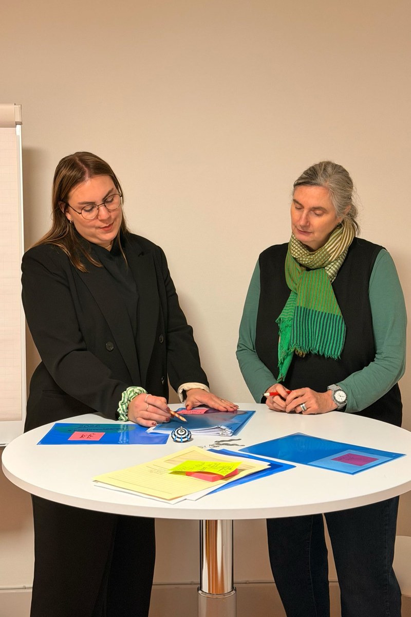 Hanja Heimann und Rosmarie Hubschmid stehen an einem Tisch und arbeiten am Fundraising-Konzept