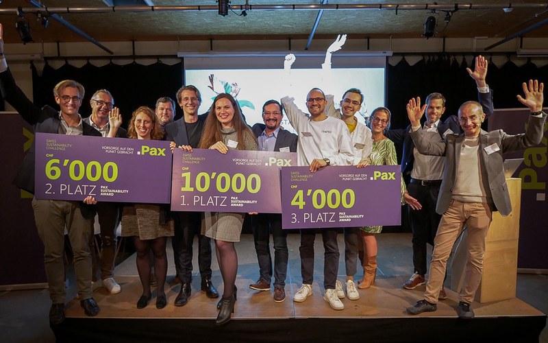 Die Gewinner*innen und Organisator*innen der Swiss Sustainability Challenge stehen auf einer Bühne und halten die Hände nach oben. Die drei Gewinner-Teams halten grosse Schecks mit dem Preisgeld in den Händen.