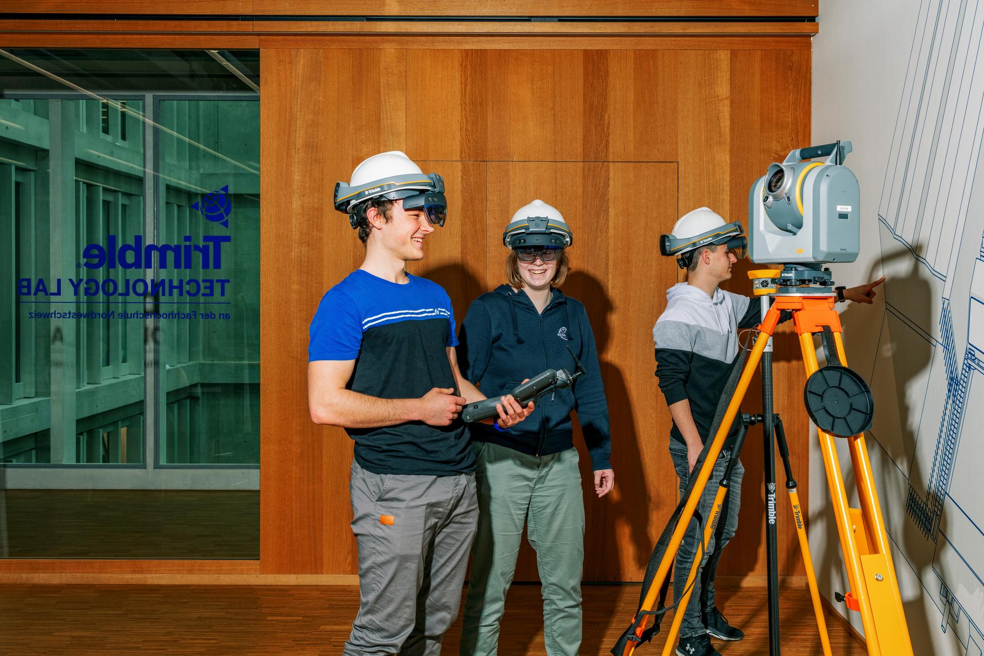 Studierende mit Bauhelmen und Virtual-Reality-Brillen und einem geodätischen Messgerät im Trimble Technology Lab