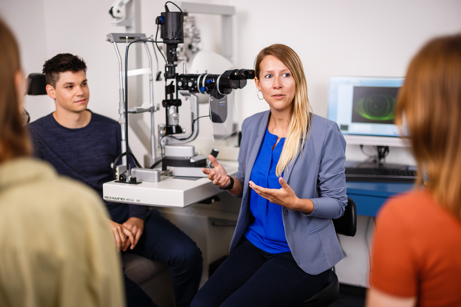 Dozentin mit drei Studierenden vor optometrischen Geräten