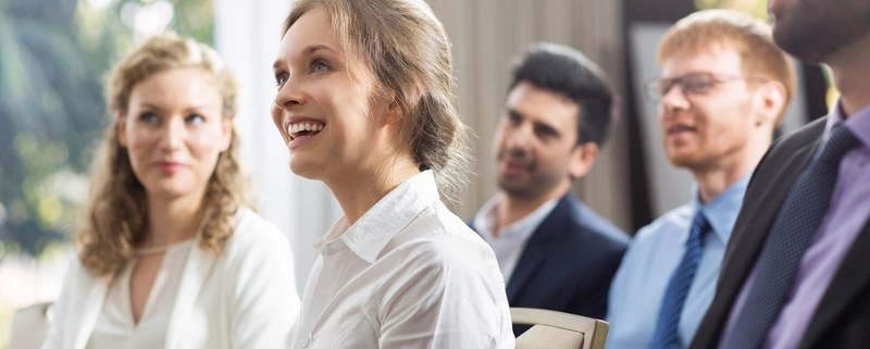 A young alumni woman member laughs into the camera