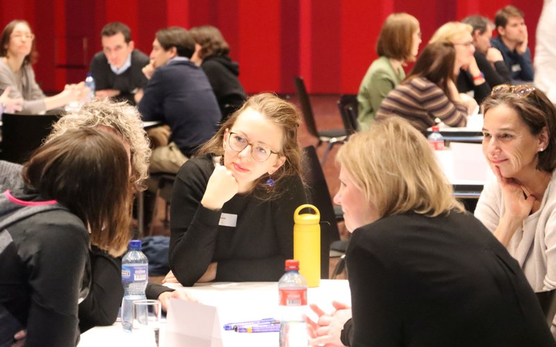 Mehrere Personen sitzen um einen Tisch und diskutieren angeregt.