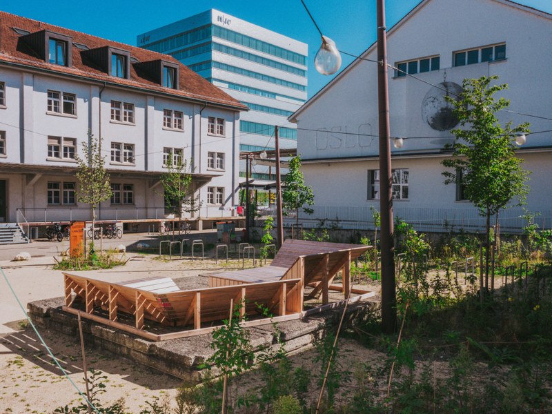 Im Vordergrund der Park mit Sitzbänken, im Hintergrund das HGK-Hochhaus