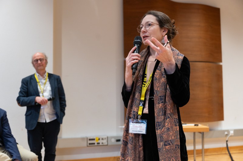 Eine Frau steht und hält ein Mikrofon in der Hand während sie spricht