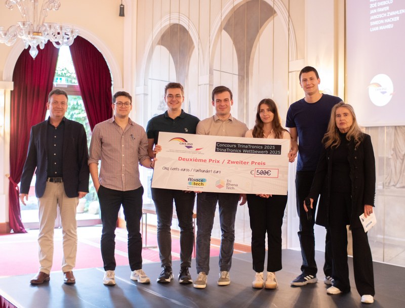 Das Team des Trinatronic-Wettbewerbs hält einen gorssen Schek