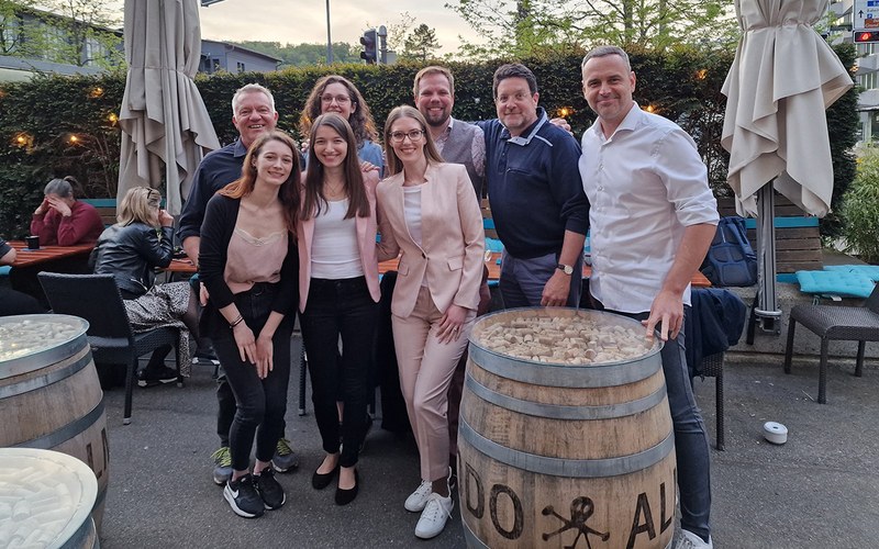 Gruppenfoto der Studierendengruppe mit dem Praxispartner. Sie stehen draussen im Garten einer Bar. 