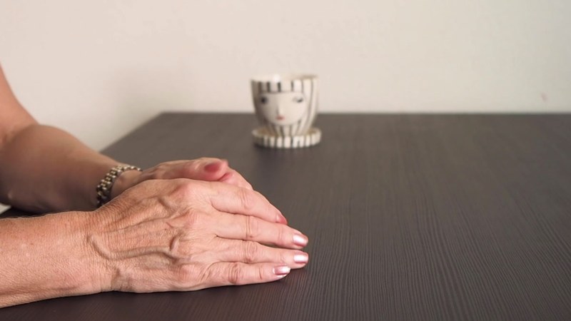 Hände einer interviewten Person liegen zusammengefaltet auf dem Tisch