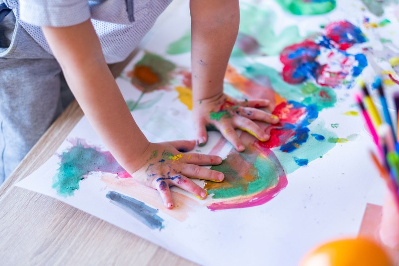 Ein Kind malt mit seinen Händen auf deinem Blatt Papier