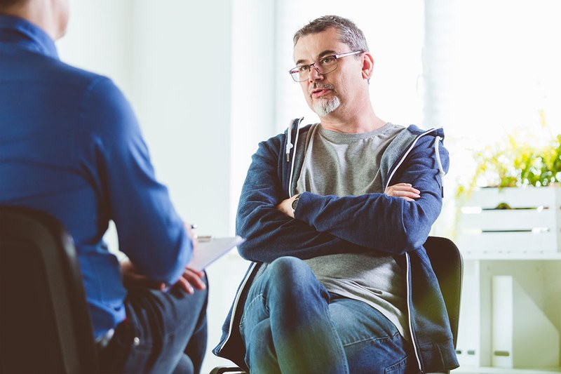 Zwei Männer sitzen gegenüber voneinander, einer ist Berater, der andere Klient.