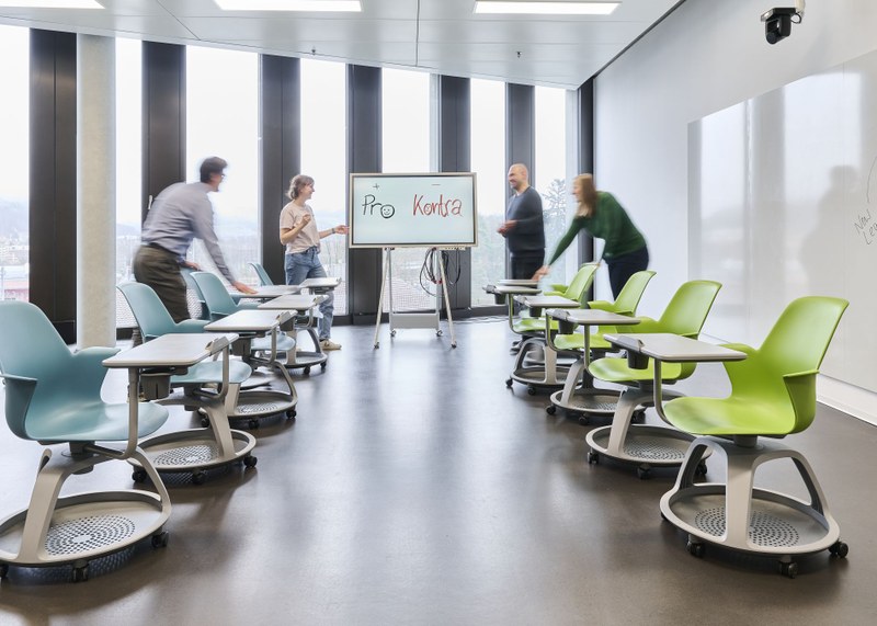 Der gleiche modulare Lernraum wie zuvor. Die Stühle sind nun zu einem gemeinsamen Klassenzimerformat vor einem Smartboard gruppiert