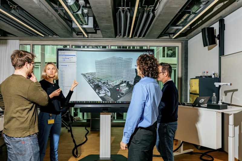 Eine Frau erklärt auf einem Smart Whiteboard anderen ein visualisiertes Gebäude