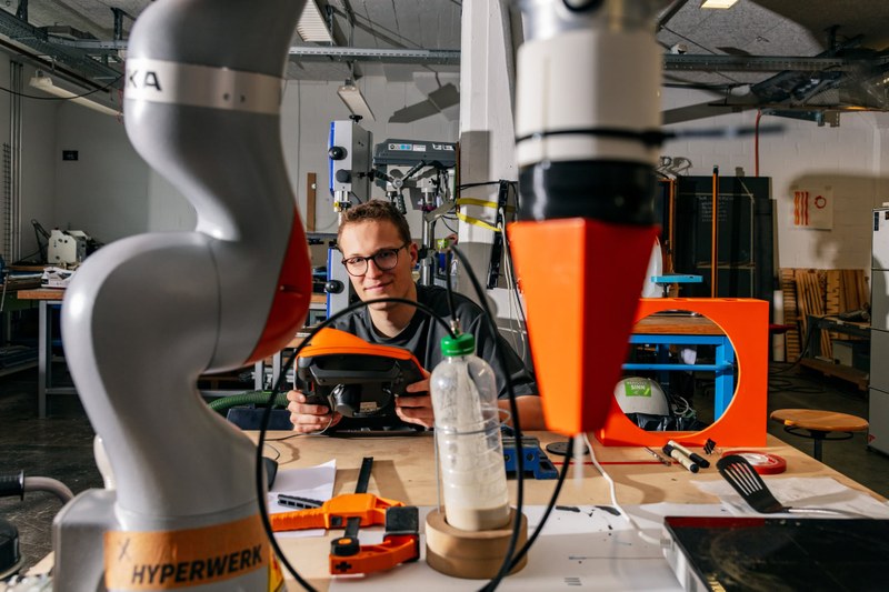 Ein Studierender in einer Werkstatt der HGK Basel arbeitet mit einem Industrie-Roboterarm