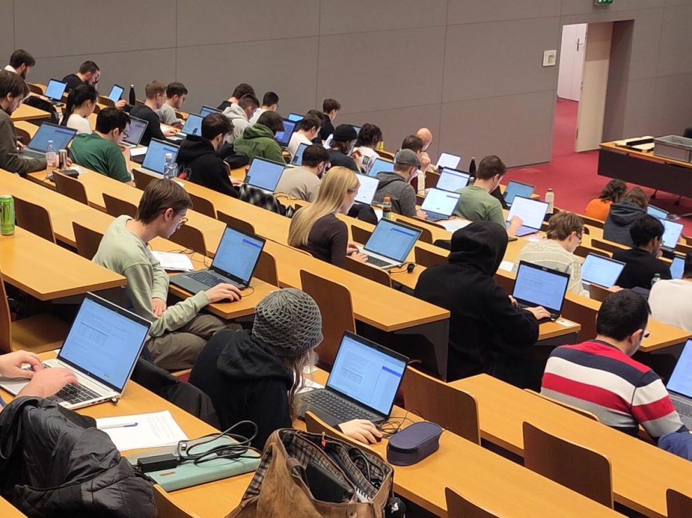 Studierende arbeiten an Laptops in Aula