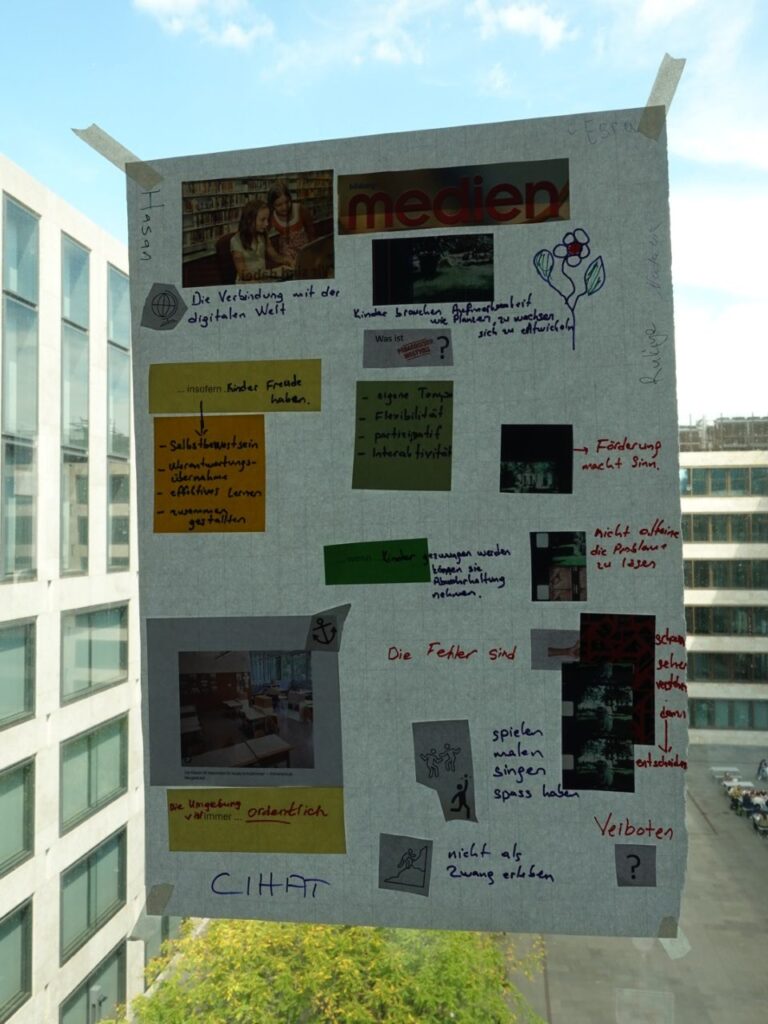 Ein Plakat befestigt an einem Fenster, das den Innenhof der PH Zürich Zeigt. Abgebildet sind Resultate einer Gruppendiskussion. Genauere Inhalte sind nicht erkenntlich.